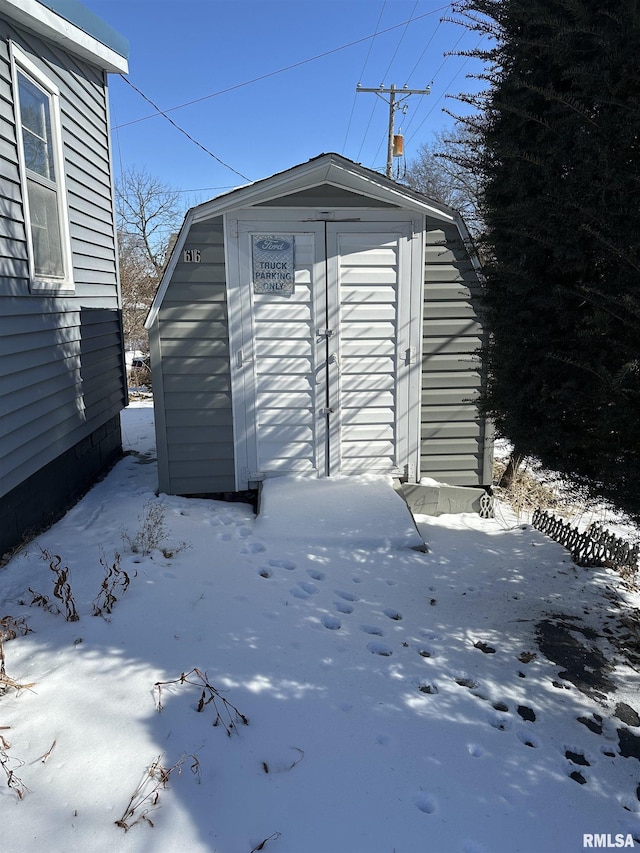 snow covered structure with an outbuilding and a storage unit