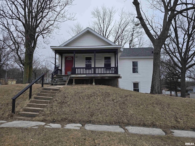 view of front of home featuring covered porch, a shingled roof, and stairs