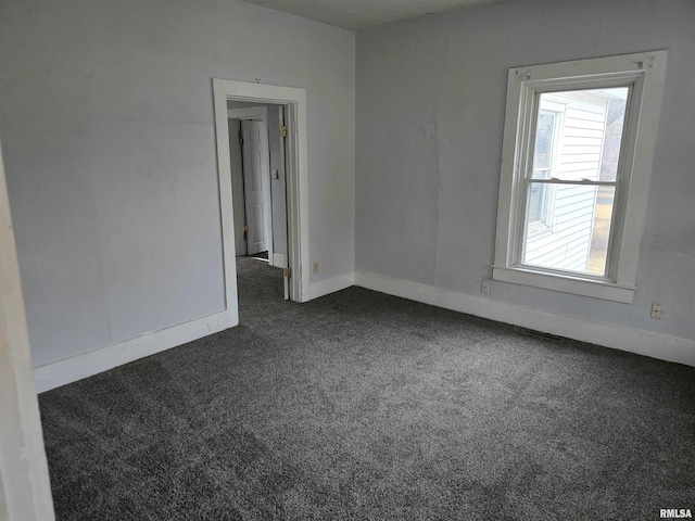 empty room featuring baseboards and dark carpet