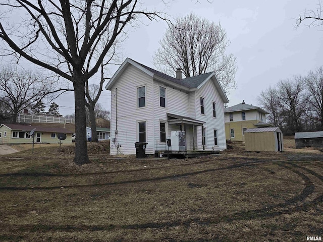 view of front facade with a storage shed, a chimney, and an outdoor structure