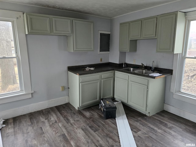 kitchen with dark countertops, a sink, dark wood finished floors, and baseboards