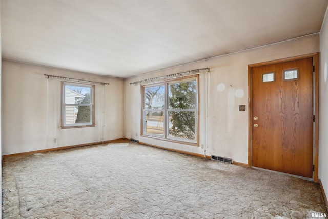 carpeted spare room featuring baseboards and visible vents