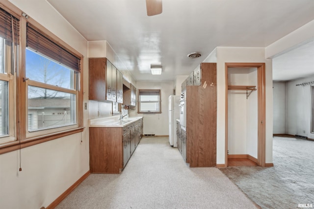 kitchen with light carpet, baseboards, freestanding refrigerator, light countertops, and a sink