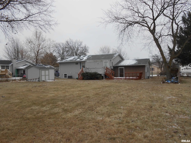 back of house featuring an outbuilding, a lawn, a wooden deck, and a storage shed