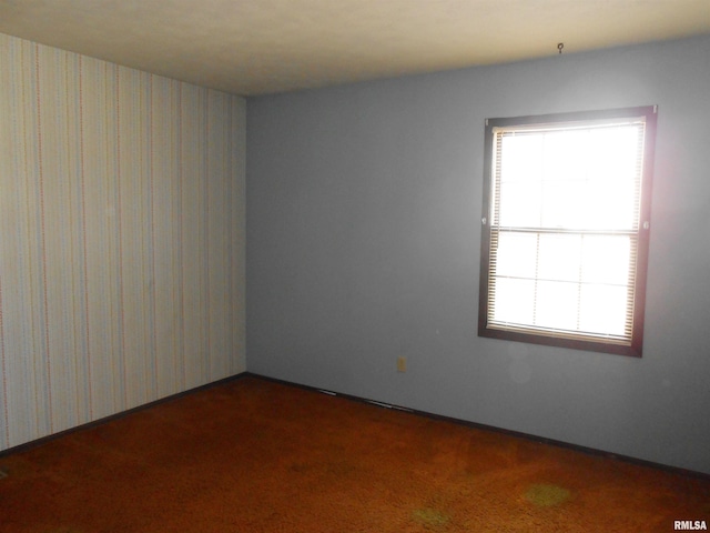 empty room with wallpapered walls and carpet flooring