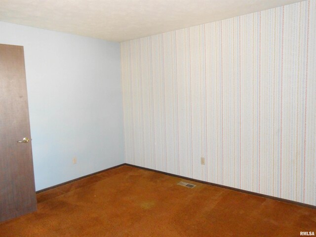 carpeted spare room with wallpapered walls, visible vents, and baseboards