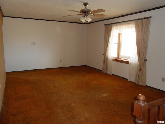 empty room featuring a ceiling fan, light colored carpet, crown molding, and visible vents