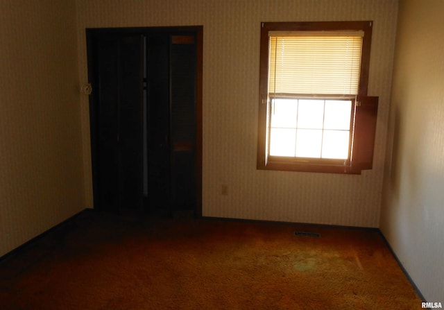 unfurnished bedroom with carpet floors, wallpapered walls, and visible vents