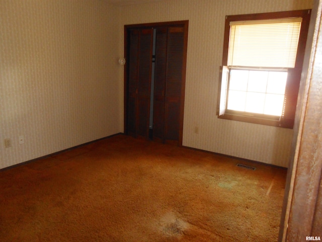 unfurnished room with wallpapered walls, visible vents, and carpet flooring