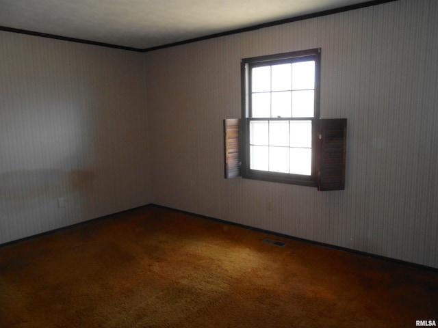 carpeted spare room featuring visible vents and crown molding