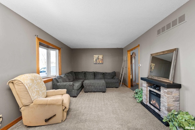 living area with baseboards, visible vents, a textured ceiling, carpet flooring, and a fireplace