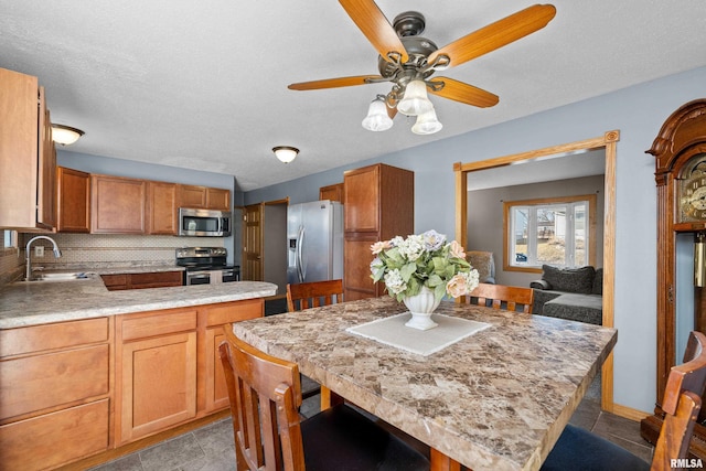 kitchen featuring tasteful backsplash, a ceiling fan, appliances with stainless steel finishes, light countertops, and a sink