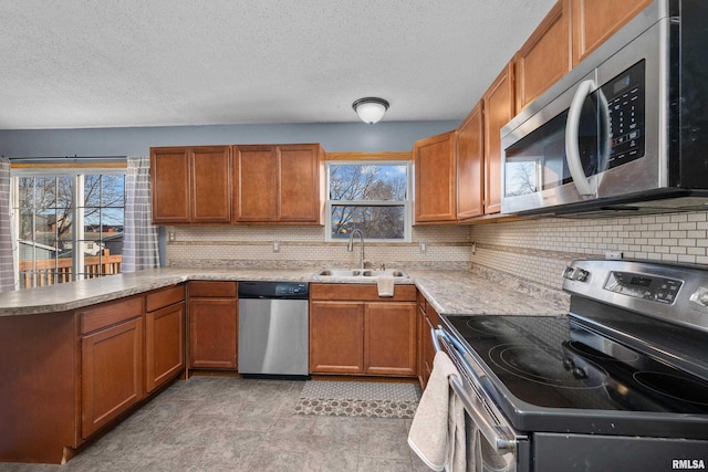 kitchen with brown cabinetry, stainless steel appliances, and a sink