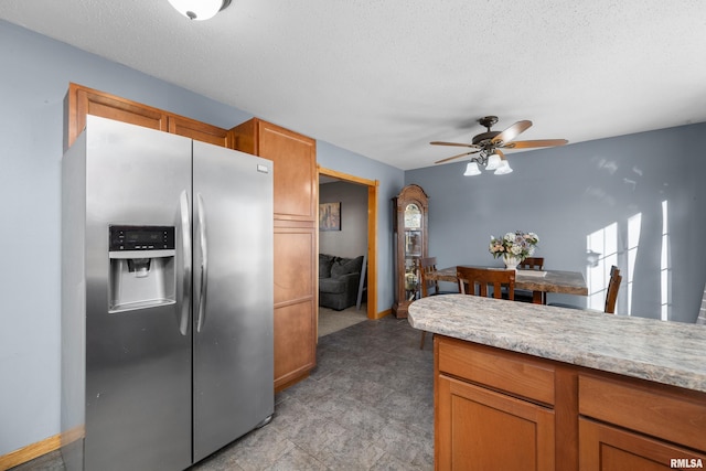 kitchen featuring brown cabinets, a textured ceiling, stainless steel refrigerator with ice dispenser, and light countertops