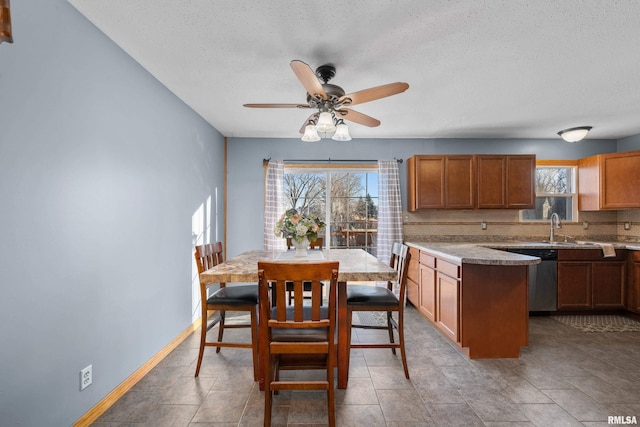 kitchen with baseboards, dishwasher, light countertops, a textured ceiling, and backsplash