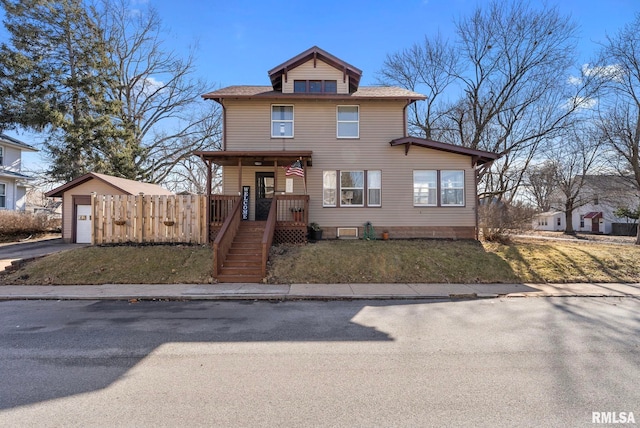 traditional style home with driveway, a detached garage, a porch, fence, and a front lawn