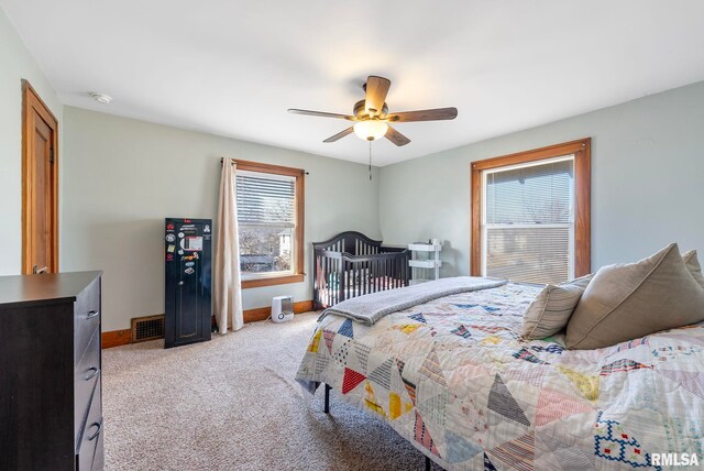 bedroom with a ceiling fan, light carpet, and baseboards