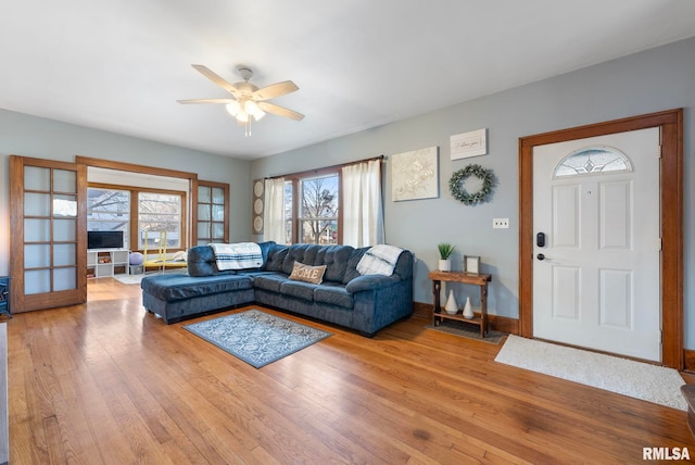 living room with baseboards, ceiling fan, and light wood-style floors