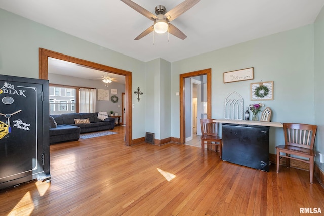 living room with light wood-style flooring, a ceiling fan, visible vents, and baseboards