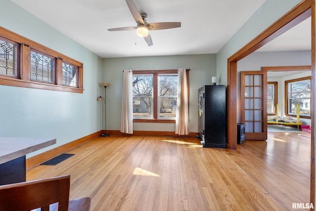 unfurnished living room with baseboards, light wood-style flooring, visible vents, and a wealth of natural light