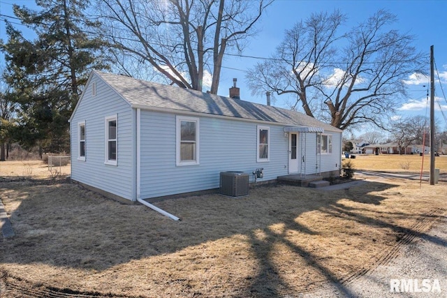 view of front of property with central AC, roof with shingles, and a chimney