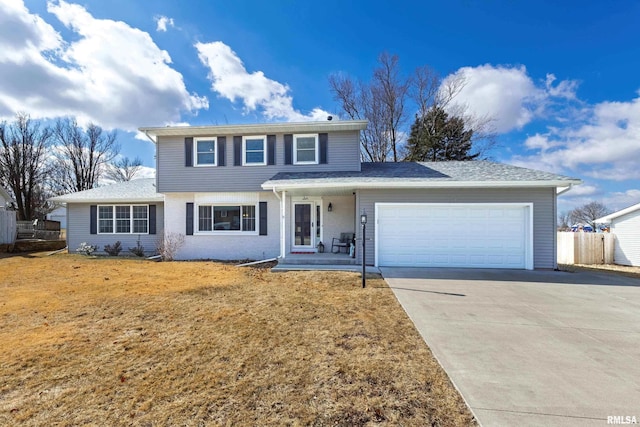 traditional-style house featuring an attached garage, driveway, fence, and a front lawn