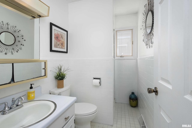 bathroom with visible vents, vanity, toilet, and tile walls