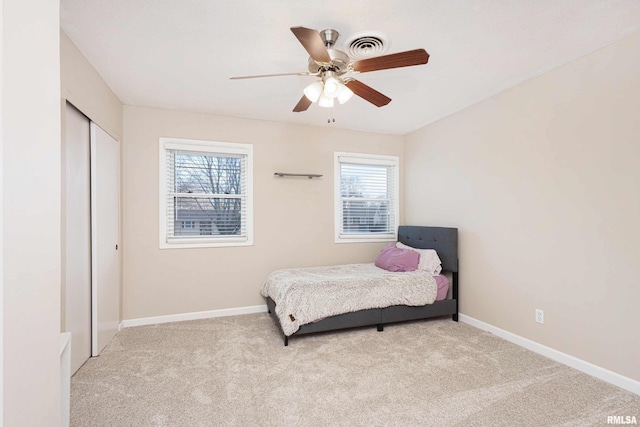 carpeted bedroom with a ceiling fan, a closet, and baseboards