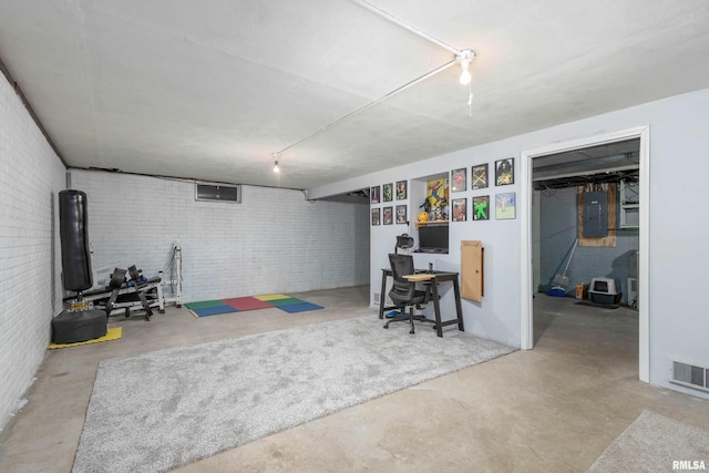 finished basement with brick wall, visible vents, and electric panel