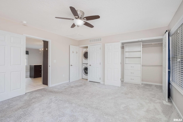 unfurnished bedroom featuring carpet, stacked washing maching and dryer, visible vents, and baseboards