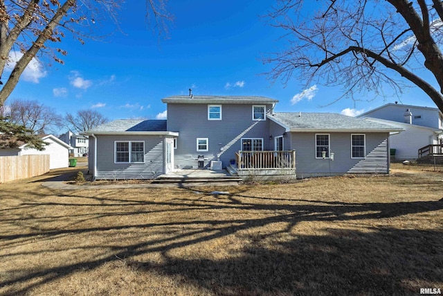 rear view of property with a lawn, a wooden deck, and fence