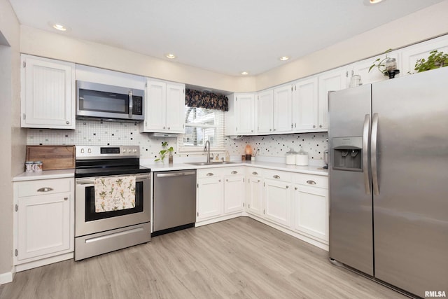 kitchen featuring light countertops, appliances with stainless steel finishes, light wood-style flooring, and white cabinetry