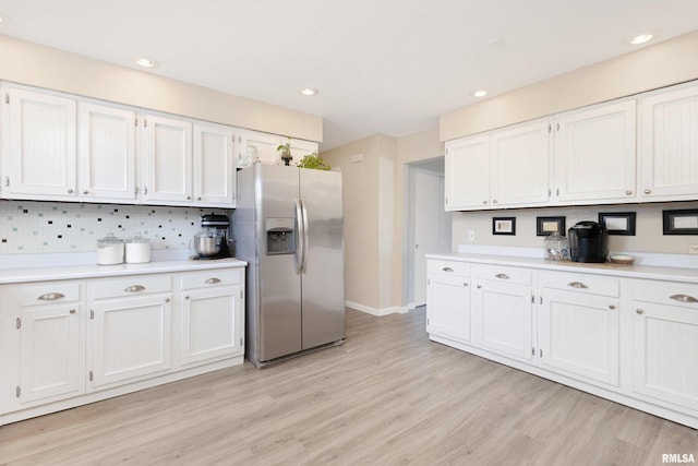 kitchen featuring white cabinetry, light wood-style floors, light countertops, stainless steel refrigerator with ice dispenser, and backsplash