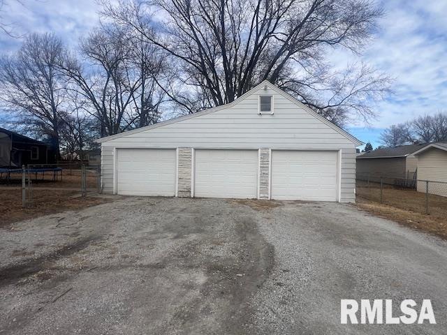 detached garage with a trampoline and fence