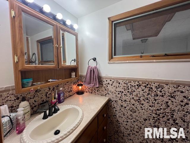 bathroom featuring a wainscoted wall, vanity, and tile walls