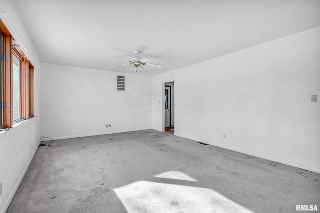 spare room with ceiling fan, carpet floors, and brick wall