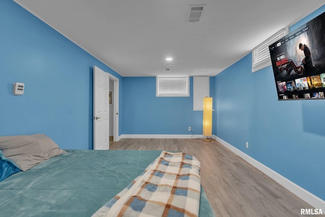 bedroom with visible vents, baseboards, and wood finished floors