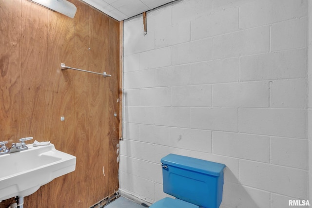 bathroom featuring concrete block wall and a sink