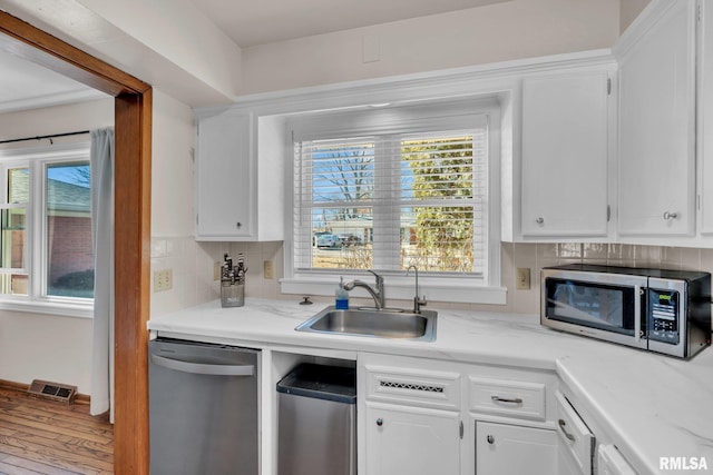 kitchen featuring appliances with stainless steel finishes, white cabinets, visible vents, and a sink