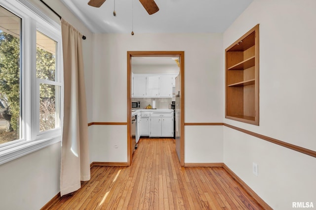 interior space featuring a wealth of natural light, light wood-type flooring, ceiling fan, and baseboards