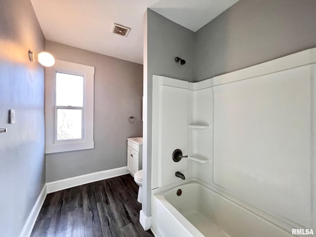 full bathroom with toilet, wood finished floors, visible vents, baseboards, and washtub / shower combination