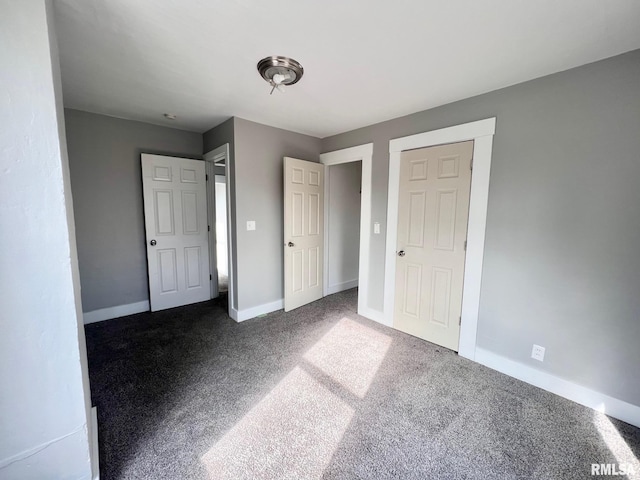 unfurnished bedroom with dark colored carpet and baseboards