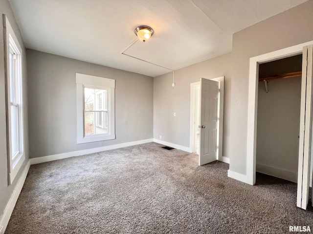 unfurnished bedroom with dark carpet, visible vents, and baseboards