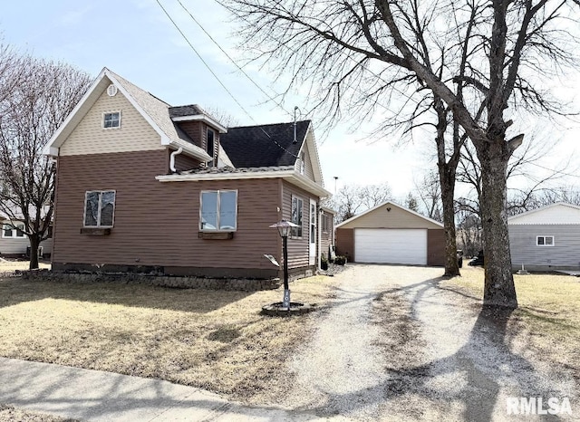 view of side of home featuring a detached garage, an outdoor structure, and a shingled roof