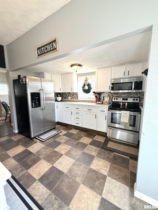 kitchen featuring a wealth of natural light, appliances with stainless steel finishes, and white cabinetry