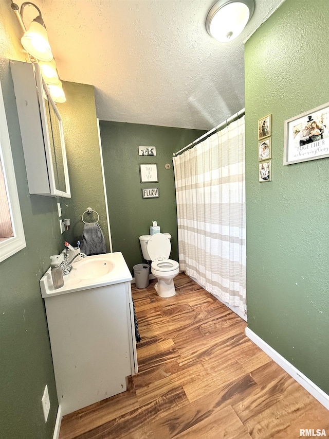 full bathroom with vanity, wood finished floors, baseboards, a textured ceiling, and toilet