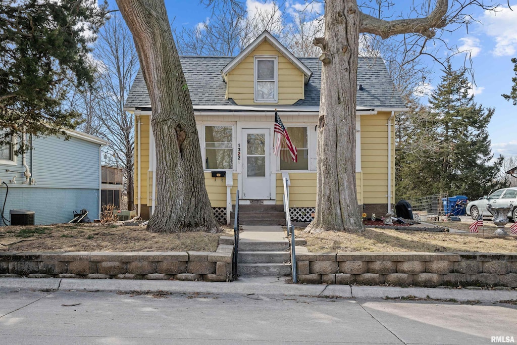 view of front of property featuring entry steps, central AC unit, and roof with shingles