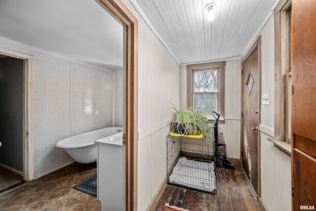 bathroom with wood finished floors, a soaking tub, tile walls, and ornamental molding