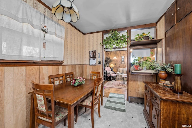 dining room featuring light floors, wallpapered walls, and wood walls