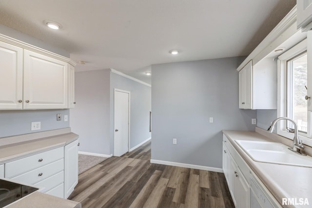 kitchen with dark wood finished floors, white cabinetry, a sink, dishwasher, and baseboards